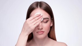 A young beautiful girl removes makeup with a cotton pad and micellar water from her face and eyes. - Powered by Shutterstock - Get 15% off with code: PIKWIZARD15