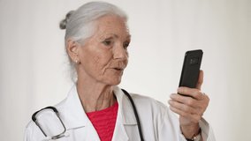 Pretty senior, elderly, mature woman doctor making video call with patient, on smartphone tele health, telemedicine concept