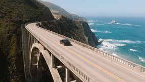 Electric car driving by scenic bridge on cinematic ocean background. Electric sedan drives by mountain coast road, scenic route. Alternative energy for cars. Eco and environmentally friendly - Powered by Shutterstock - Get 15% off with code: PIKWIZARD15