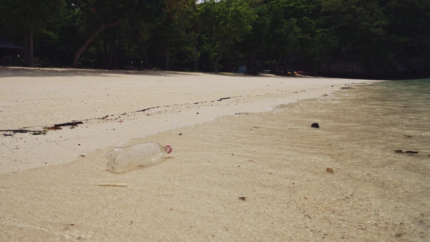 Rubbish on Beach, Single Use Plastic Bottle in Waves on Sandy Shore of White Sand, Garbage Trash and Waste Causing a Human Impact on Marine Conservation and Water Pollution in Asia Royalty-Free Stock Footage #1092887195