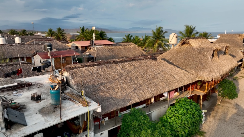 Chacahua, Oaxaca, Mexico. Aerial fly drone view of a virgin beach and jungle tropical town paradise with ocean and tourquese water with palms and incredible scenary with contructions on the beach.