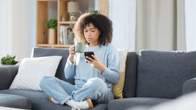 Woman reading a text message on a phone, scrolling on social media online or browsing an app while drinking coffee at home. One happy, smiling and comfy black female searching the web with tea - Powered by Shutterstock - Get 15% off with code: PIKWIZARD15