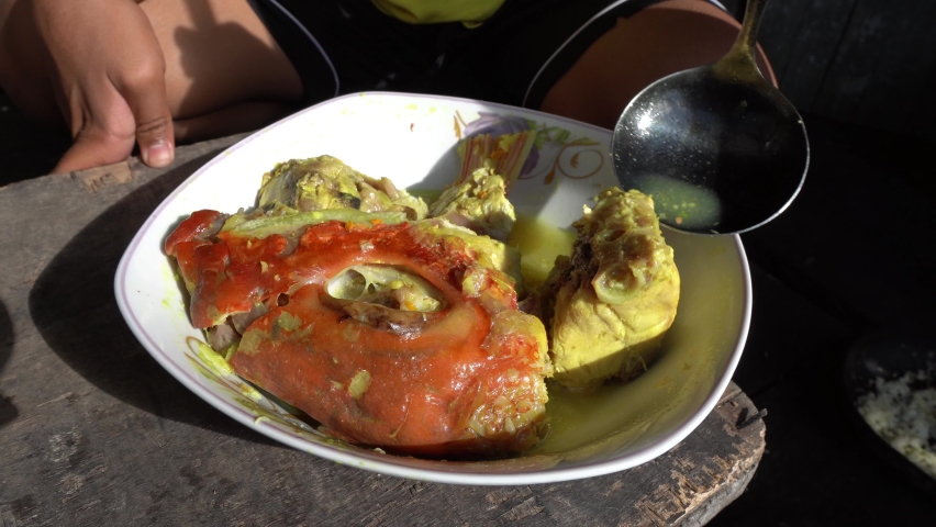 The hand of an Indonesian cook who is preparing a menu of tropical fish sauce that is given a natural yellow dye using turmeric