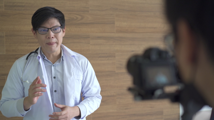 Asian specialist doctor making an online video live streaming. Behind the screen showing doctor talking to the camera. Royalty-Free Stock Footage #1092900343