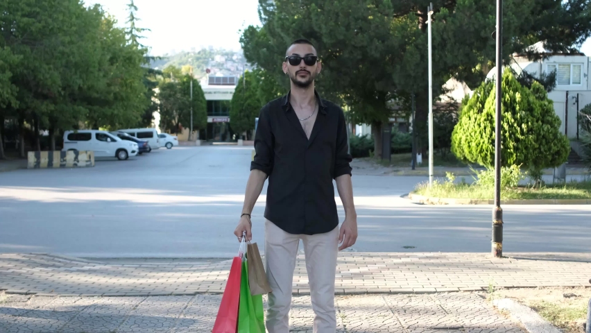 Shopping is happiness message, young man showing like sign by showing the bags in his hand, young man showing his happiness back from shopping