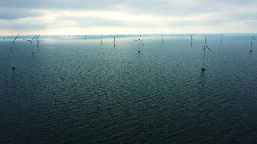 Aerial drone shot of oceanic wind turbines at the Rødsand wind farm in Denmark. Green energy is a promising alternative to fossil fuels and the need for a transition is urgent.  | Shutterstock HD Video #1092902219