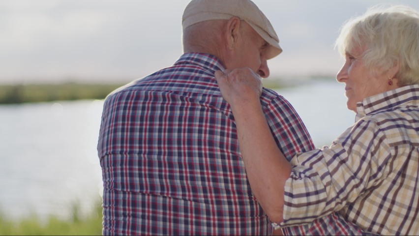 Happy smiling old couple hugging sitting on lake beach in sunshine close up outdoor. Loving harmony, marriage idyllic, romantic relationships, care and support, tender embraces of married grandparents Royalty-Free Stock Footage #1092906263
