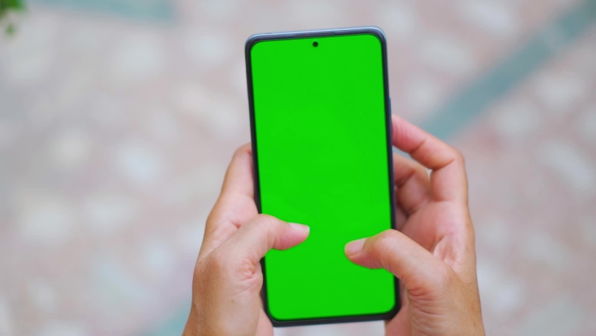 Female hand holding smartphone with green screen. Using mobile phone at home. Chroma key, close up Indian woman hand holding phone with vertical green screen. | Shutterstock HD Video #1092915155