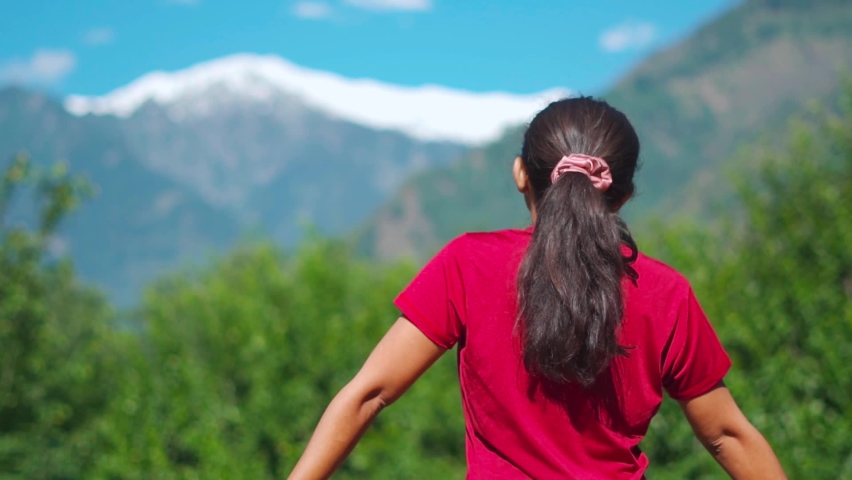 Rear view of teenager Indian girl traveler looking at snow capped mountain. Tourist in Manali, Himachal Pradesh, India. The girl enjoys being in the mountains. Camping. Leisure. | Shutterstock HD Video #1092915157