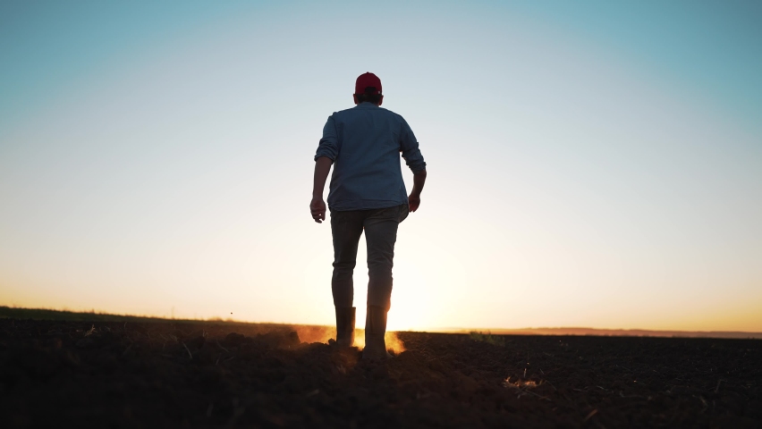Agriculture. farmer at sunset walk on fertile soil. Farm worker silhouette. The foot of a man in rubber boots walk through the mud. Farmer agronomist works on land plot at sunset. Agriculture concept Royalty-Free Stock Footage #1092916987