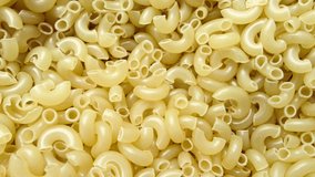 Stop motion video with yellow pasta. Video of shuffling noodle horns. Screensaver with food from flour products. 4K stock video.