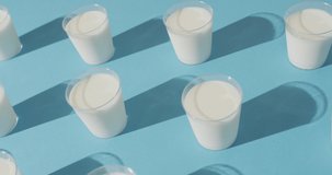 Video of row of glasses of milk on blue background. dairy products and healthy organic nutrition.