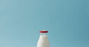 Video of glass bottle of milk on blue background. dairy products and healthy organic nutrition.