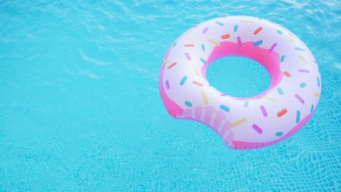 Pink inflatable donut ring floating in clear blue swimming pool. Top view. Summer colorful background. Vacation, relax. tropical concept. Copy space