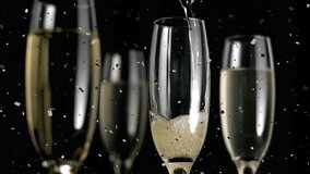 Animation of confetti over glasses of champagne on black background. Party and celebration concept digitally generated video.