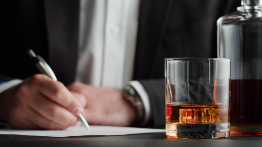Businessman drinking brandy or whiskey close-up. Rich man drinks luxury cognac while working. Alcohol amber rum, liqour beverage in glass. Royalty-Free Stock Footage #1092926071