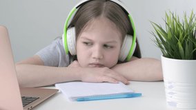 Caucasian homeschooling girl feeling bore to do homework. Kid making boring face when working on computer at home. Children remote online education. Back to school