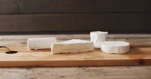 Video of assorted soft cheeses on chopping board, on wooden table with copy space. quality, tasty light food snack.