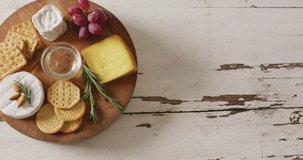 Video of cheese, biscuits, grapes and rosemary on wooden board and rustic table top with copy space. quality, tasty light food snack.