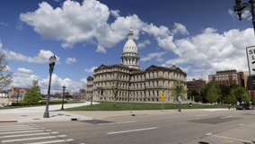 Michigan state capitol building in Lansing, Michigan with ground level time lapse video showing slow moving clouds with zoom in.