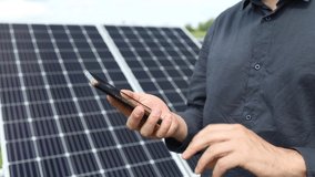 a man holds a smartphone near solar panels on a plot near the house. - Powered by Shutterstock - Get 15% off with code: PIKWIZARD15