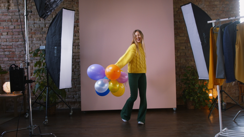 Fashion studio shooting of a happy young woman with balloons , backstage of photoshooting . Royalty-Free Stock Footage #1092940277