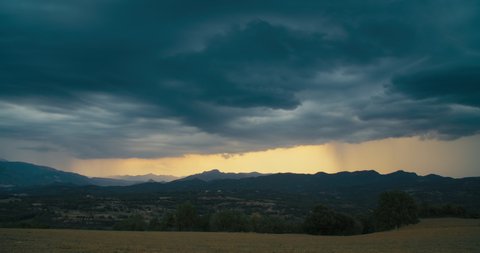 Timelapse stormy cloudscape on rural environment with mountains in horizon. Hyperlapse of rain at sunset on epic nature scenery.
