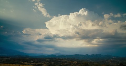 Timelapse of growing white cloud replaced by rainy dark sky. Epic nature landscape hyperlapse in 4k resolution. Countryside field and mountains on horizon