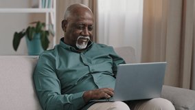 Older bald African American man 60s senior mature businessman use easy wireless technology for comfort work online shopping ecommerce at home couch typing massage chatting banking in computer app - Powered by Shutterstock - Get 15% off with code: PIKWIZARD15