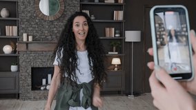 Young ridiculous comical hispanic woman recording vlog on telephone joyful girl blogger filming trendy dance video challenge performs popular moves happy female records music content funny dancing