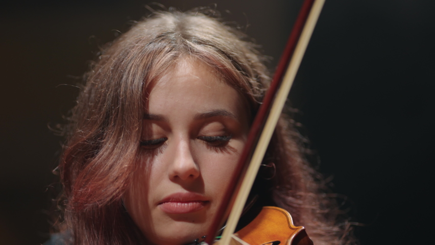 closeup portrait of beautiful female violin player, woman violinist is playing fiddle in opera house Royalty-Free Stock Footage #1092946717