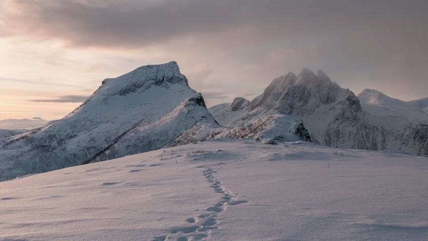 Time lapse of Sunrise over snowy mountain peak with footprint on winter in the morning at Segla mount, Senja island, Norway