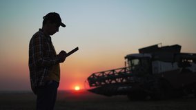 Agriculture. Harvester harvests wheat field at sunset. Silhouette of farmer with tablet in wheat field.Harvesting at sunset.Agricultural business.Farmer controls harvesting of wheat grain by combine - Powered by Shutterstock - Get 15% off with code: PIKWIZARD15