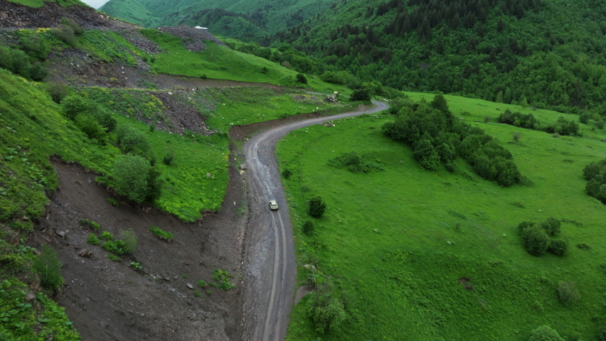Car Driving On Dirt Road In A Hillside Near Ushguli Village In Georgia - aerial shot