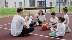 Male trainer explaining game strategy to kids on the basketball court. Diverse kids team and coach discussing game tactics. Education and sport concept. Back view - Powered by Shutterstock - Get 15% off with code: PIKWIZARD15