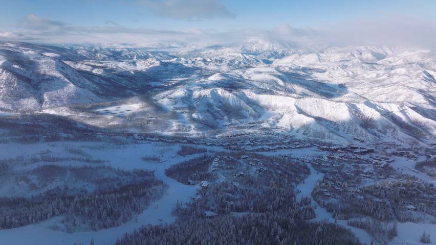 Aerial forward Epic winter snow-covered mountains surrounding Snowmass village ski resort, Colorado abstract natural landscape. Ski slopes on mountain terrain. Cinematic sunny winter day background | Shutterstock HD Video #1092963427
