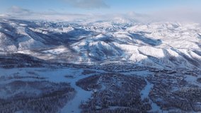 Aerial forward Epic winter snow-covered mountains surrounding Snowmass village ski resort, Colorado abstract natural landscape. Ski slopes on mountain terrain. Cinematic sunny winter day background - Powered by Shutterstock - Get 15% off with code: PIKWIZARD15