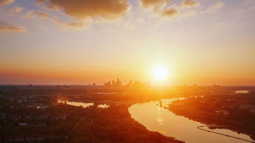 Aerial time lapse hyperlapse beautiful sunset over modern city, golden hour cityscape, skyline. Warsaw city panorama and Vistula river lit with warm evening sun light. Drone shot, urban scene