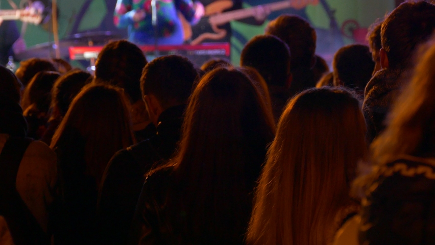 Ungraded: Unrecognizable crowd of spectators at rock concert waving their hands, jumping, dancing and shooting a concert on smartphones. Ungraded H.264 from camera without re-encoding. Royalty-Free Stock Footage #1092967761