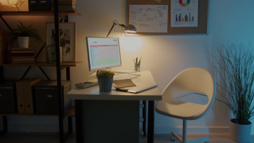 Zoom-out of modern open space office with workplaces and equipment and no people at night. Business location and interior concept. Royalty-Free Stock Footage #1092970921