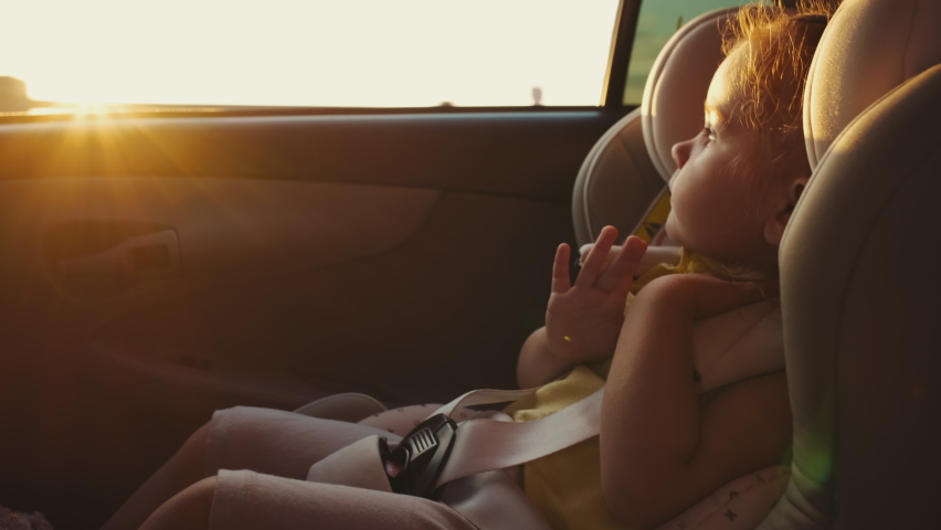 The child sits in a child car seat while the car is moving and looks out the window. Travel concept,Funny life,Summer Time | Shutterstock HD Video #1092973125