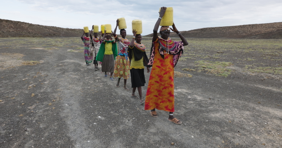 Climate change,drought,water crisis.Close-up front view.African woman walking home after collecting water in plastic containers from a volcanic spring, Turkana region, Kenya Royalty-Free Stock Footage #1092979473