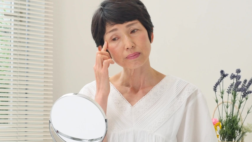 Asian senior woman looking in the mirror at home  Royalty-Free Stock Footage #1092979655