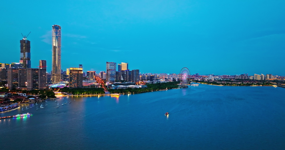 Aerial footage of city skyline and modern commercial buildings with lake natural scenery in Suzhou at night, China.