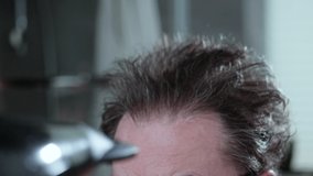 The man is drying his crazy hair, thinning hair. Slow motion video.