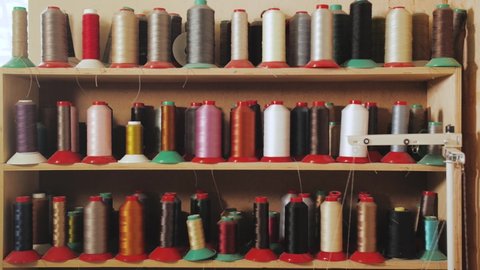 The camera moves from assorted spools of thread on shelves in shoemaker workshop, slow motion.