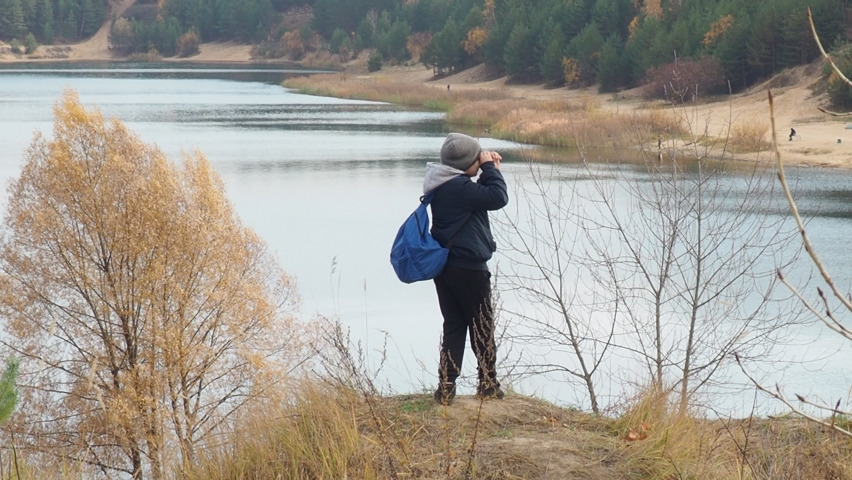 boy with a tourist backpack walks along the lake in autumn. Tourism, camping, hiking. time in nature. child hikers enjoying the view at the top of a mountain in the fall