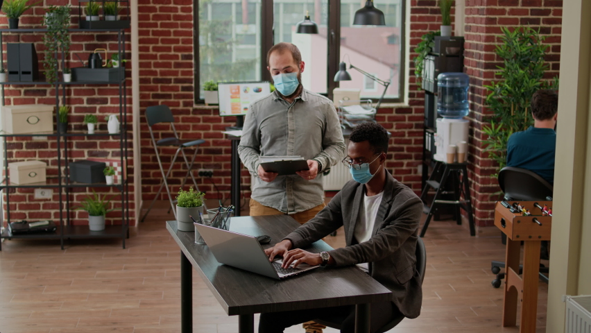 Business men with face mask doing teamwork on startup project, working with data charts and statistics to plan corporate presentation. Diverse people at office job during pandemic. | Shutterstock HD Video #1092993471
