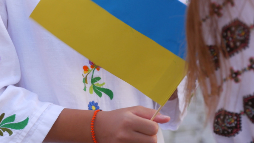 Blue-yellow flags of Ukrainians in the hands. People in national Ukrainian embroidered vyshyvanka costumes hold flags in their hands at a demonstration rally in support of Ukraine | Shutterstock HD Video #1092994957