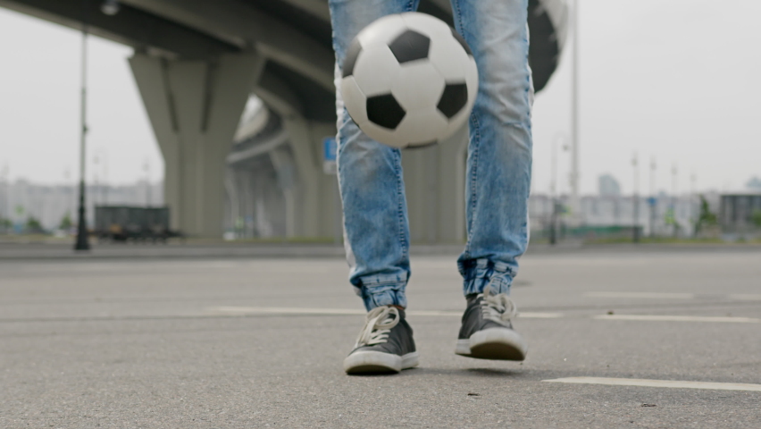 Freestyler juggles football using toes under overhead road | Shutterstock HD Video #1092996299